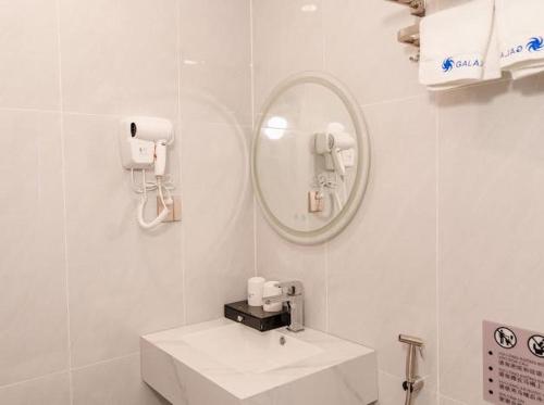 a white bathroom with a sink and a mirror at Galaxy Hotel Móng Cái in Móng Cái