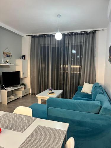 a living room with a blue couch in front of a window at Vala Mar Residence Shima in Draçi