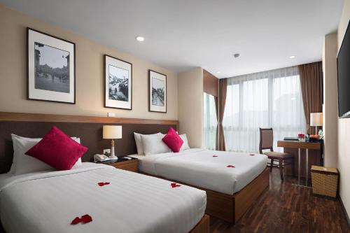 a hotel room with two beds with red roses on them at Golden Moon Suite Hotel in Hanoi