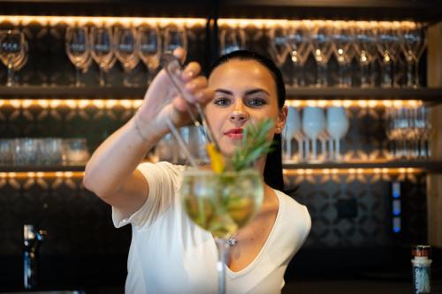 a woman is stirring a drink in a glass at Moar's Hotel in Valdaora