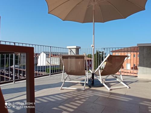 a pair of chairs and an umbrella on a balcony at Vialeromadodici Rooms & Apartments in Lazise