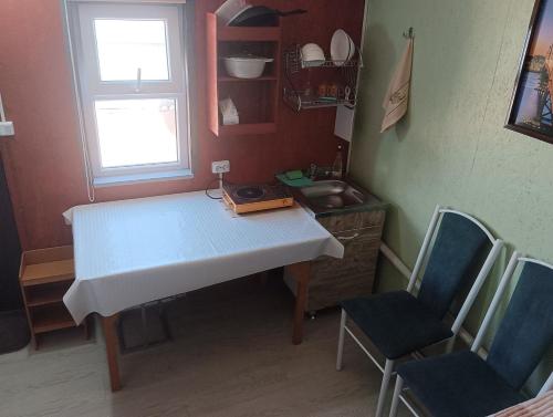 a small kitchen with a table and two chairs at Восток Долинка in Cholpon-Ata
