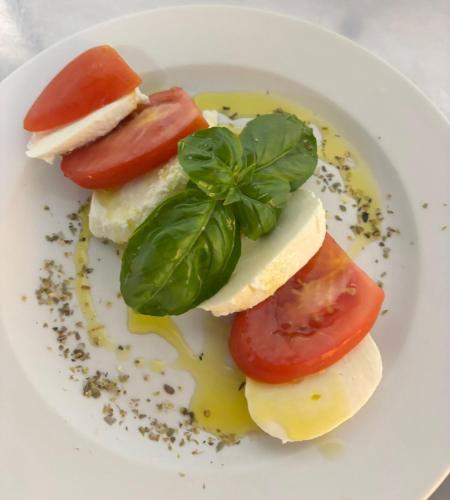 a plate of food with tomatoes and basil on it at Hotel Garisenda B&B - in Centro a Riccione - in Riccione