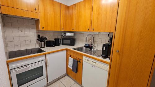 a small kitchen with wooden cabinets and a sink at Studio 4103 Les Sources aux Bains d'Ovronnaz in Ovronnaz