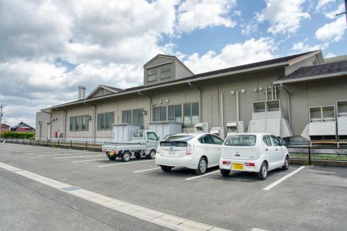 a building with three cars parked in a parking lot at 高島市一棟貸切可能貸別荘グループファミリーok 大人数でご利用だとお得連泊がお得BBQ可能自転車無料利用可ペット可 駅徒歩10分 in Takashima