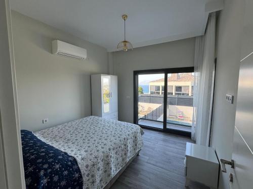 a bedroom with a bed and a large window at Kaptan Villas in Çeşme