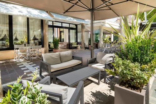 an outdoor patio with chairs and tables and plants at Hotel Novella in Misano Adriatico