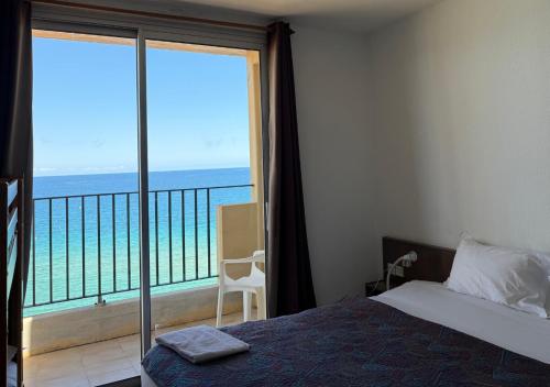 a bedroom with a bed and a view of the ocean at Hôtel A RENA D'ORU in Coggia