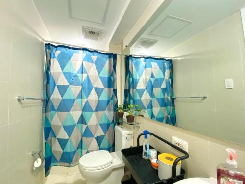 baño con aseo y cortina de ducha azul en Azure North Staycation - Bali 2115 Unit, en San Fernando