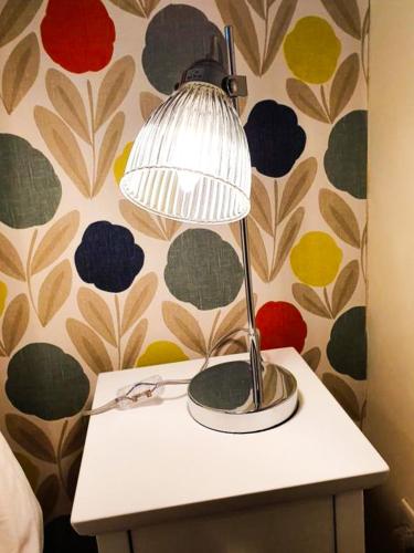 a lamp on top of a table with a wall at The Lodge Stanwell in Stanwell