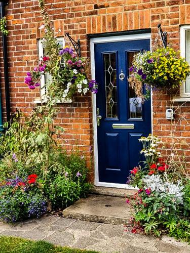 a blue door on a brick house with flowers at The Lodge Stanwell in Stanwell