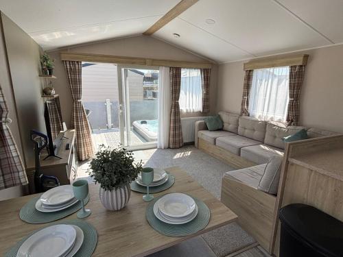 a living room with a table and a couch at Sunnymede B5 - Fantasy Island - HOT TUB, ramped decking, patio doors, central heating, pet friendly - Meadow Lakes Caravan & Lodge Hire in Ingoldmells
