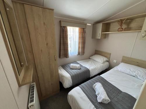a small room with two beds and a window at Sunnymede B5 - Fantasy Island - HOT TUB, ramped decking, patio doors, central heating, pet friendly - Meadow Lakes Caravan & Lodge Hire in Ingoldmells