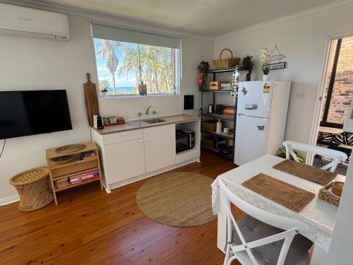 a kitchen with a white refrigerator and a table and a sink at Paradise on Jones Beach Kiama - Beachfront unit with direct beach access & views in Kiama Downs