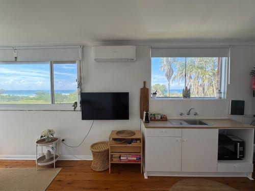 a kitchen with white cabinets and a sink and two windows at Paradise on Jones Beach Kiama - Beachfront unit with direct beach access & views in Kiama Downs
