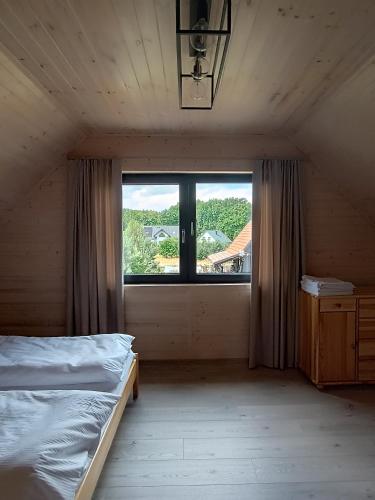 a bedroom with a bed and a large window at Szumiące Drzewa in Debina