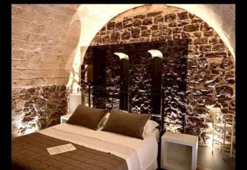 a bedroom with a bed in front of a stone wall at Il Campanile Premium B&b in Altamura