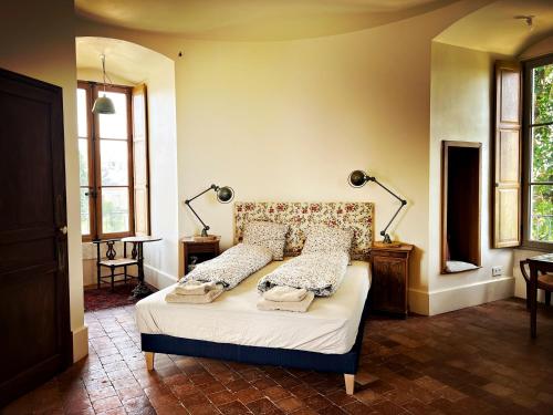 a bedroom with a bed with two lamps and windows at La Tour Beurdelaine in Avallon