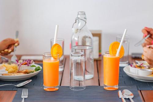 a table with glasses of orange juice and plates of food at Sands Garden Hotel in Thoddoo