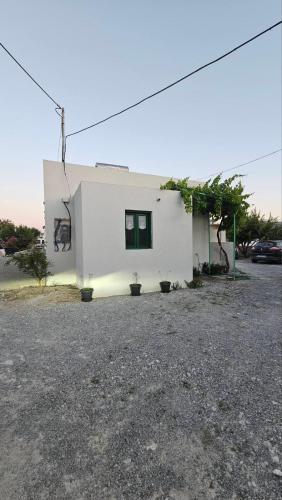 a white building with two windows in a parking lot at PAME apartments in Kámpos