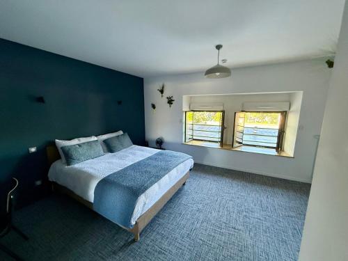a blue bedroom with a bed and two windows at Le Billot in Bologne