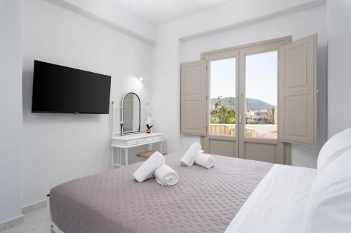 a white bedroom with a bed with two white towels at NEW Yiota Collection 4 Suites & 4 Prive Jacuzzi in Megalokhori