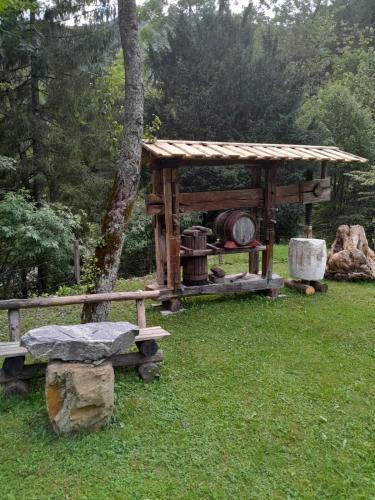 a wooden gazebo and a bench in the grass at Hiša pod Rogatcem - studio in Luče