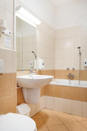 a bathroom with a sink and a tub and a toilet at Hotel Anna Villa in Balatonföldvár