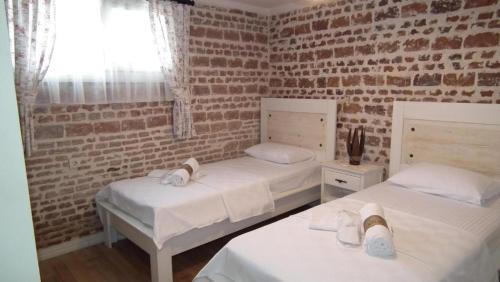 a bedroom with two beds and a brick wall at Gizemli Konak in Ayvalık