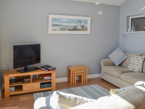 a living room with a couch and a television at Grays Cottage in Sewerby