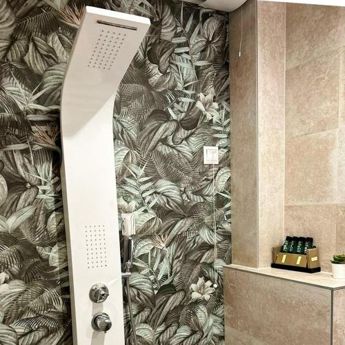 a bathroom with a shower with a tropical wallpaper at City Gate Hotel Airport Thessaloniki in Thessaloniki