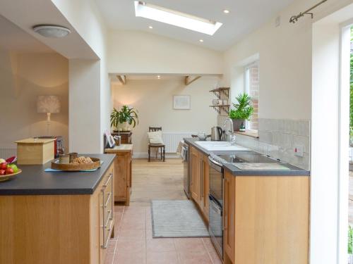 a kitchen with wooden cabinets and black counter tops at The Coach House in Great Ryburgh
