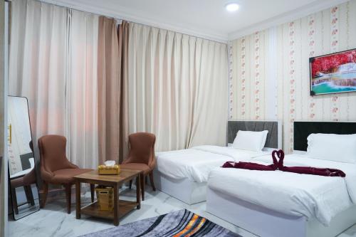 a hotel room with two beds and a table and chairs at hotel rose garden فندق روز جاردن in Duqm