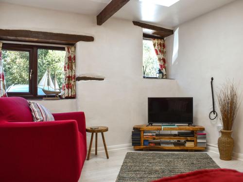 a living room with a red couch and a flat screen tv at Tarow Cottage in East Looe