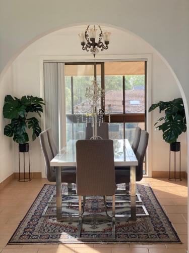 a dining room with a glass table and chairs at Bradburry Lovely The Outlook in Campbelltown South