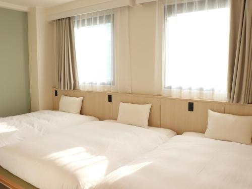 two beds in a room with two windows at Shin-Osaka Station Hotel in Osaka