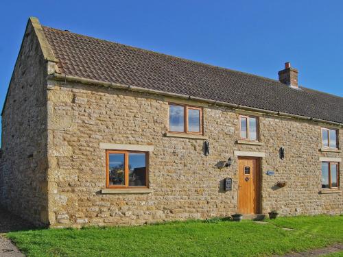 an old stone house with a brown door and windows at Featherstone Cottage in Pickering
