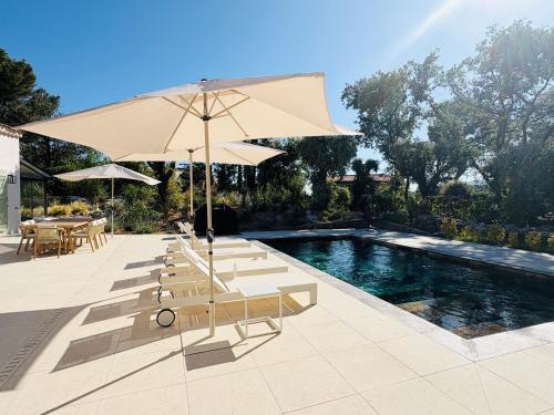 a pool with a group of chairs and an umbrella at L'Esprit Sud, 4 Suites & Piscine in Vence
