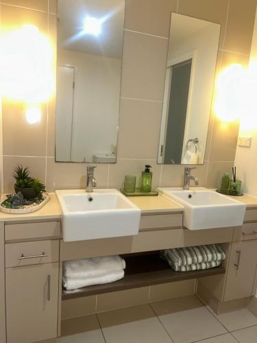 ein Badezimmer mit zwei Waschbecken und einem großen Spiegel in der Unterkunft Paradise resort living one bedroom apartment in Westcourt