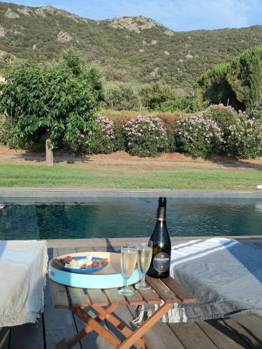 - une table avec une bouteille de vin et deux verres dans l'établissement Villa Callochiusa avec piscine 15mn Bonifacio, à Figari