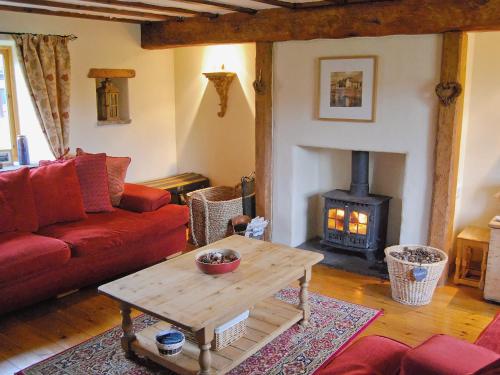 ein Wohnzimmer mit einem roten Sofa und einem Holzofen in der Unterkunft Featherstone Cottage in Pickering