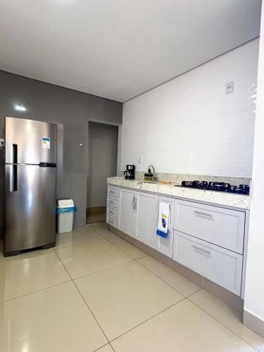 a kitchen with a stainless steel refrigerator and white cabinets at Cobertura Premium • 120m² • Conforto e Estilo in Patos de Minas