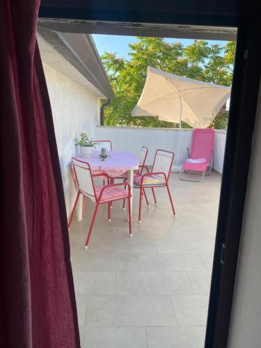 a patio with a table and chairs and an umbrella at Relax Apartments Grazia in Funtana