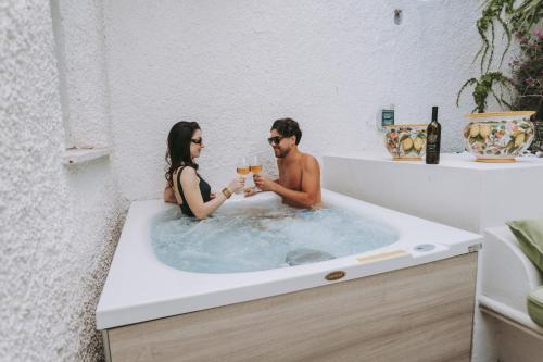 a man and woman sitting in a bathtub with glasses of wine at Villetta La Dolce Vista in Conca dei Marini