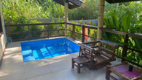 a swimming pool with a bench and a chair at Siargao Sunset Bay Beach Villas in General Luna