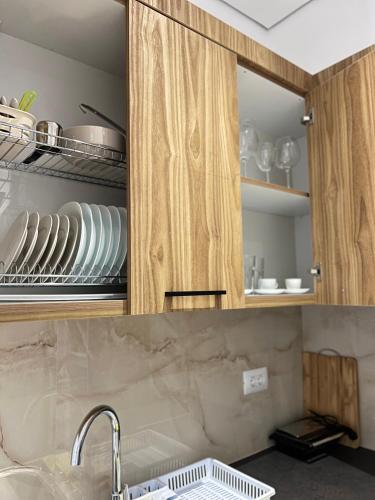 a kitchen with wooden cabinets with plates and dishes at Inscape Apartments in Sarandë