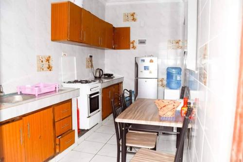 a small kitchen with a table and a refrigerator at HawiHomes in Mombasa