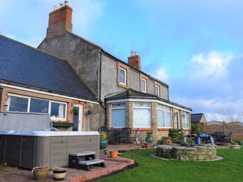 a house with a backyard with a hot tub at The Old Farmhouse in Ancroft