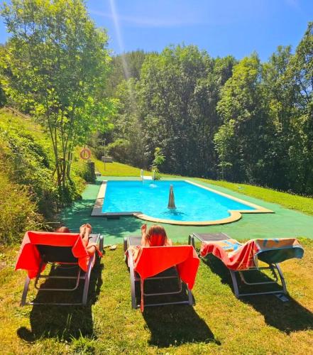 two women sitting in lawn chairs in front of a swimming pool at La Masia del Batlle in Sarroqueta