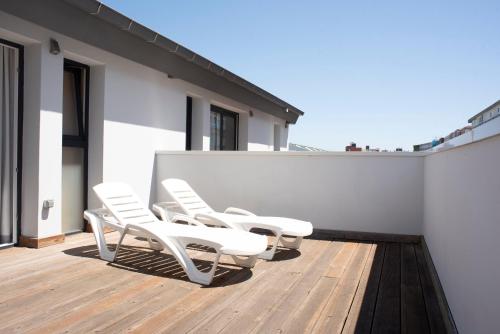 a group of white chairs sitting on a deck at Hotel Náutico Santander in Santander